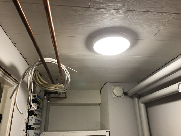 Nylagd innertak med infälld taklampa, elledningar och kopparrör i förgrunden.