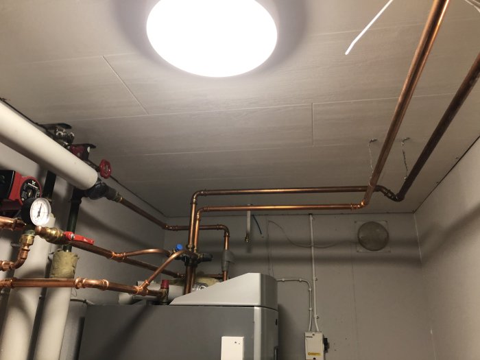 Nylagt tak med synliga kopparledningar och cirkulärt takfönster i ett teknikrum.