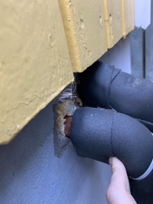 Isolerade VVS-rör genom husvägg, möjlig källa till vibrationer och ljudöverföring.