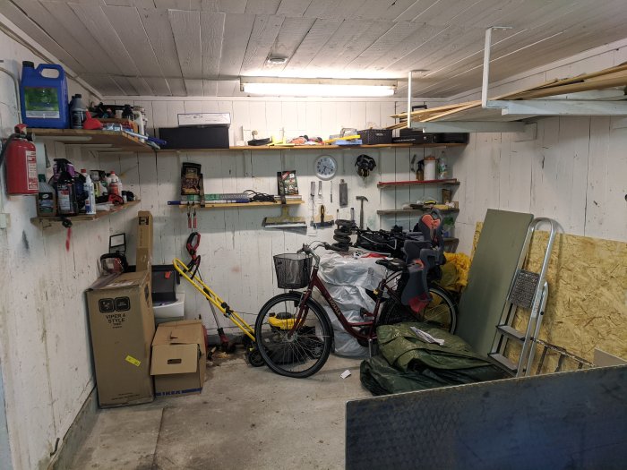 Garage med hyllor, verktyg och cyklar under nyinstallerade downlights, väntande på ytterligare förbättringar.