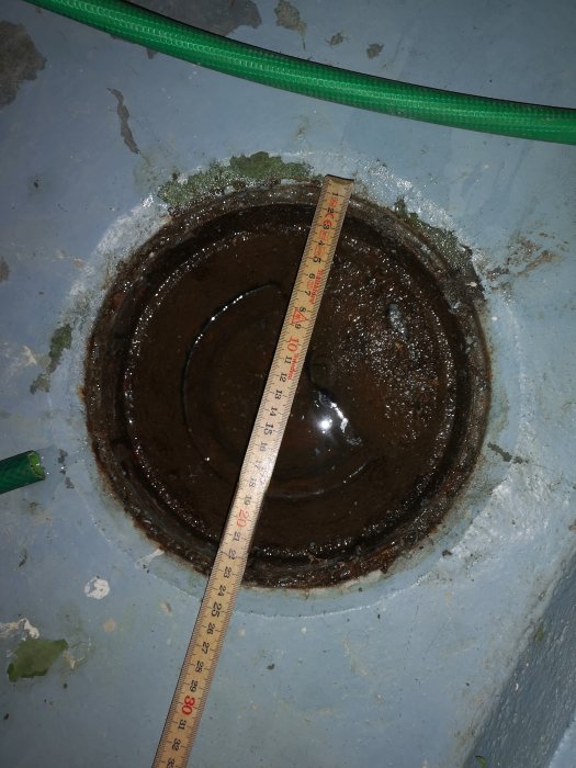 Måttband som visar diameter på brunnen i en renoveringsprojekt för källartoalett.