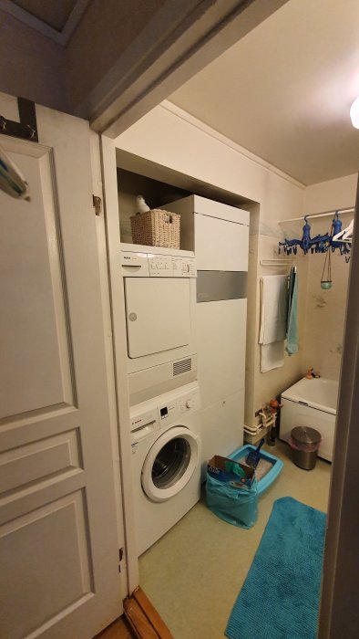 Stor vit värmepanna som tar upp utrymme i ett litet badrum med tvättmaskin och hyllor.