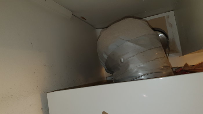 Stor varmvattenberedare installerad i ett hörn täckt med isolering i ett badrum.