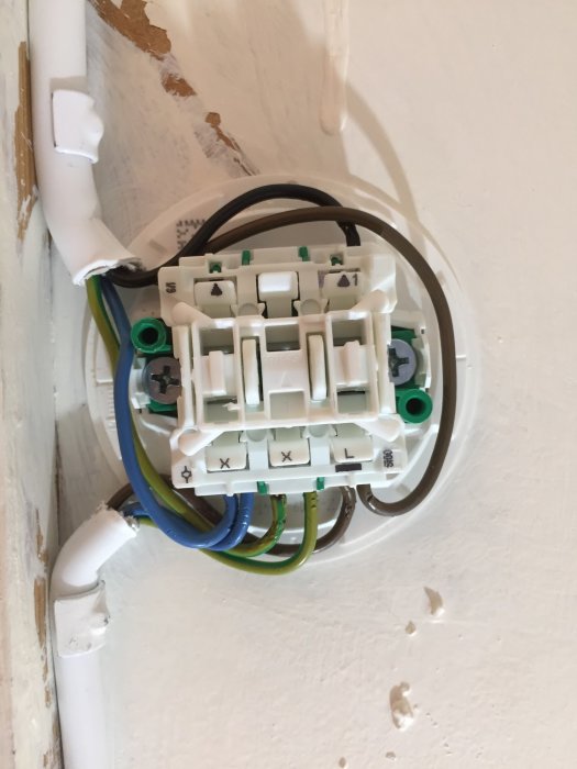 Elektrisk installationsdosa öppnad på vägg med synliga anslutna kablar innan slutmontering.