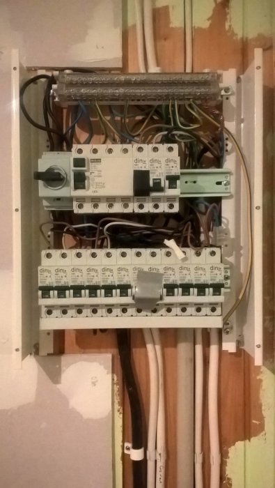 Öppen elcentral med två rader säkringar och fasskenor, några lediga platser synliga.