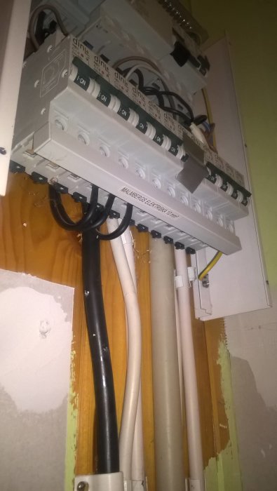 Öppen normcentral med två rader av säkringsmoduler och kablar som ansluter till dem.