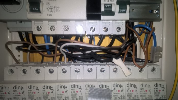Normcentral med två rader av säkringsmoduler och ihopkopplade ledningar, fem tomma platser synliga.