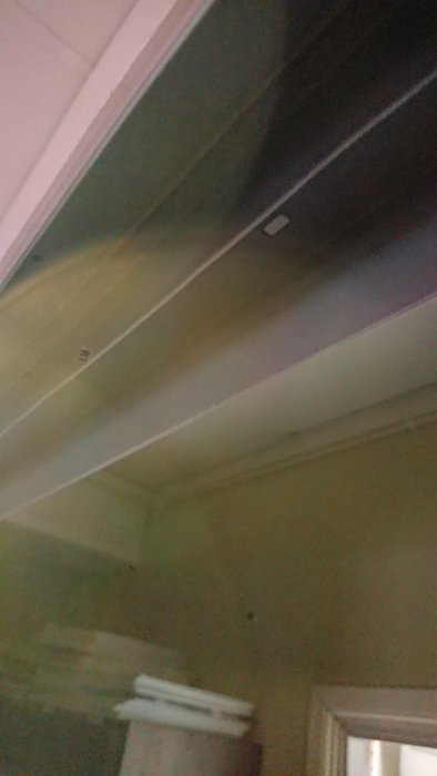 Monterade skenor i taket för gardinsystem, synligt i ett halvmörkt rum.