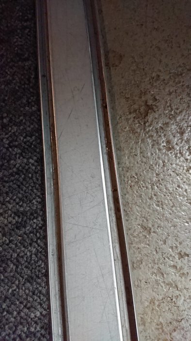 Metallskena mellan matta och betonggolv, illustrerar korrekt installation.