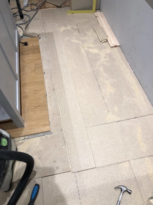 Renoveringsarbete med halvlagt laminatgolv och verktyg synliga.