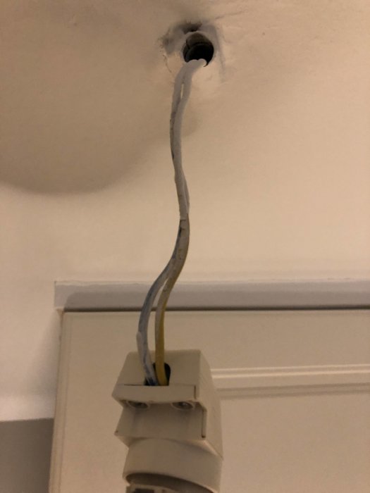 Ett öppet lamputtag i ett tak med synliga kablar och en omonterad armatur.