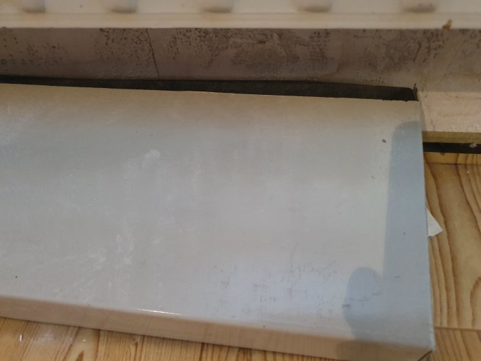 Detaljerad bild av golvlist och dess övergång till en vägg med synlig glipa.