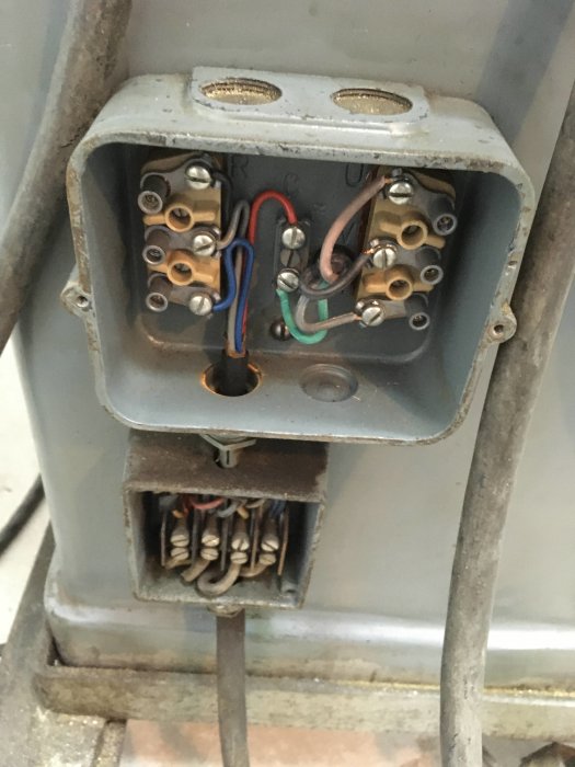 Interiören av en elektrisk kopplingsdosa med kablar och skruvklämmor, tecken på reparation syns.