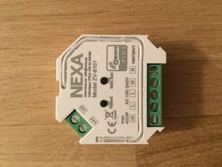 Nexa Z-wave dosdimmer liggande på ett träbord, synliga anslutningsklämmor och etiketter.