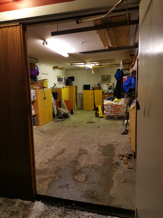 Interiör av ett garage som förberetts för installation av golvvärme, med paket och byggmaterial.