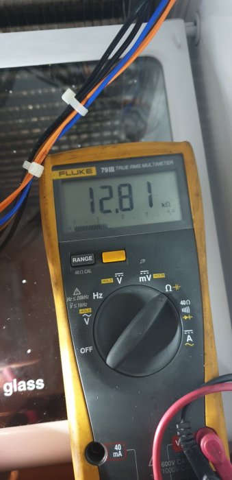 Multimeter visar 128.1 kΩ under felsökning av avfrostningselement i kylskåp.