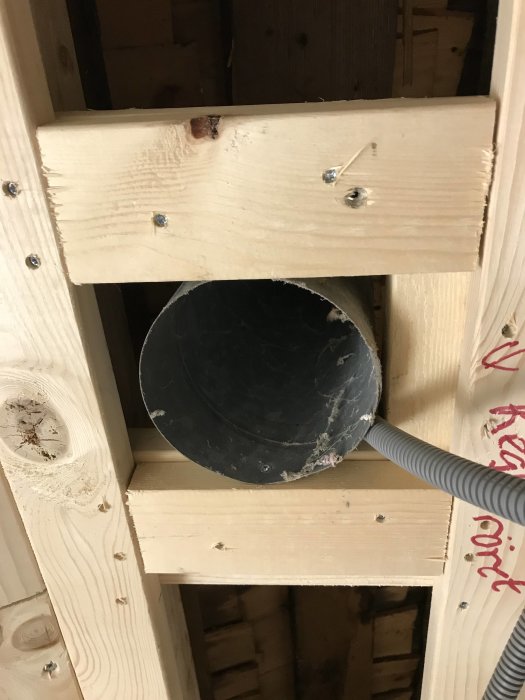 Ventilationsrör i trästomme mot gipsplattetak, redo för Paxfläktinstallation i badrum.