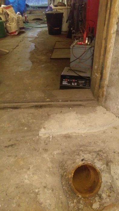 Ett avloppsrör av gjutjärn sticker upp från ett källargolv, tänkt att kopplas till wc.