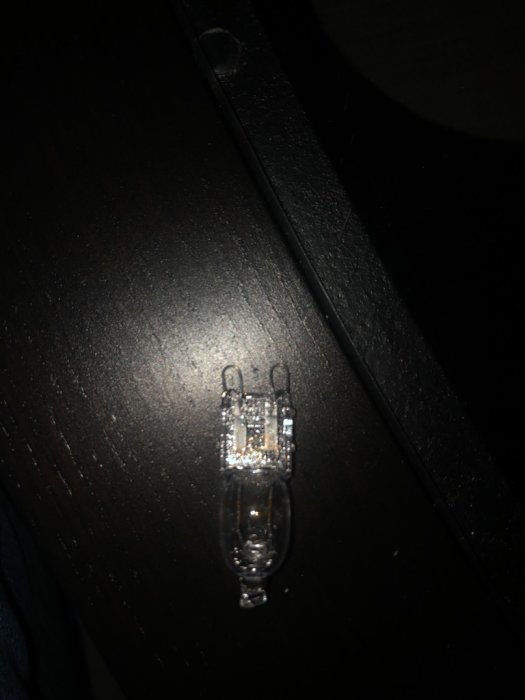 Halogenlampa på mörk bakgrund, med fokus på lampans konstruktion och glödtrådar.