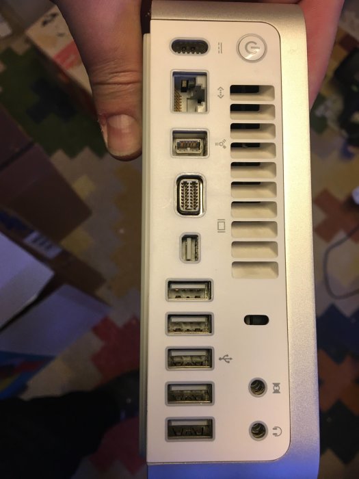 Hand håller en enhet med olika datorkontakter, inklusive USB, HDMI, och nätverksport.