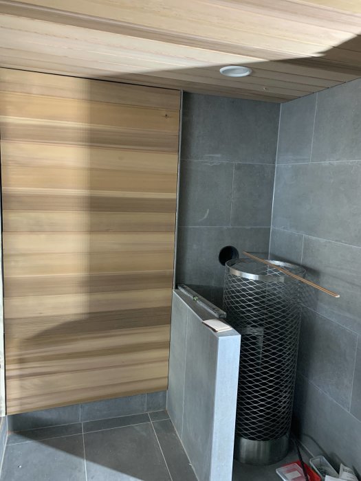 Nyinstallerad vägg med träpanel i modern badrumsinteriör med grå kakel.