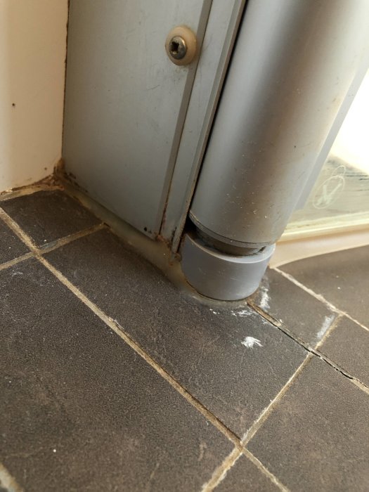 Duschhörnas nederdel med synliga sprickor och lossande silikon vid dörr och kakel.