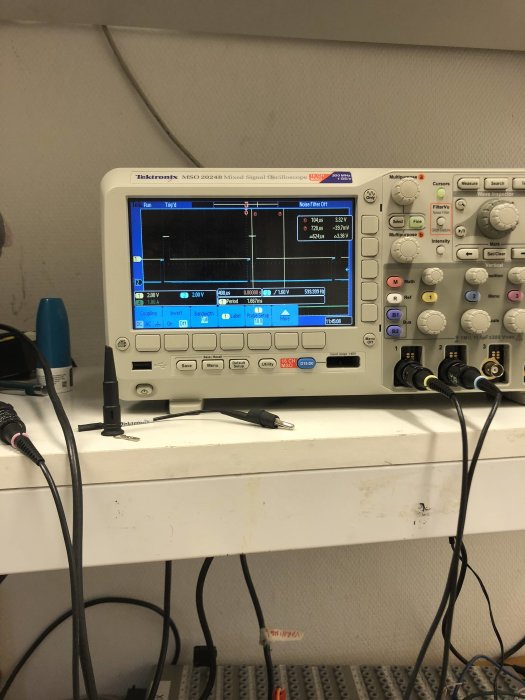 Tektronix blandat signaloscilloskop på ett laboratoriebord med synliga vågformer på skärmen och uppkopplade testkablar.