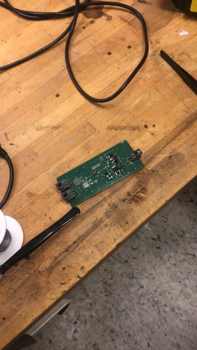 Elektroniskt kretskort från Ikea-produkt med komponenter och anslutningsstycken, ligger på ett arbetsbord med verktyg.