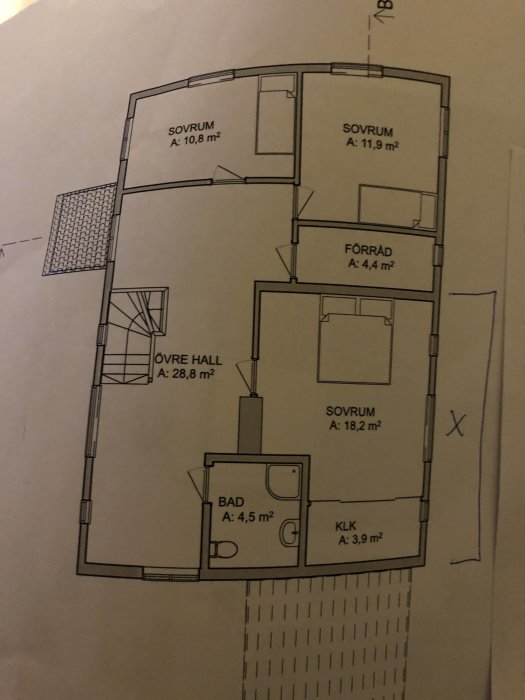 Arkitektritning av en övervåning med sovrum, badrum och förvaringsutrymmen, befintlig byggnad markerad med X.