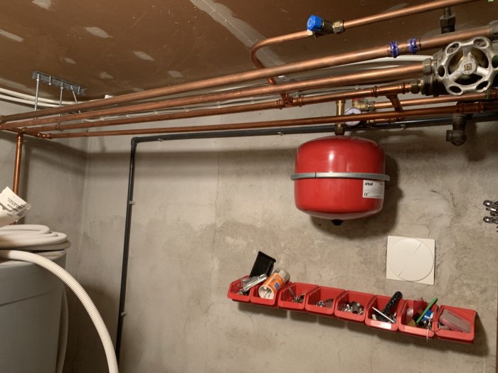 Kopparledningar och expansionskärl i ett pannrum, två ledningar går till elementen.