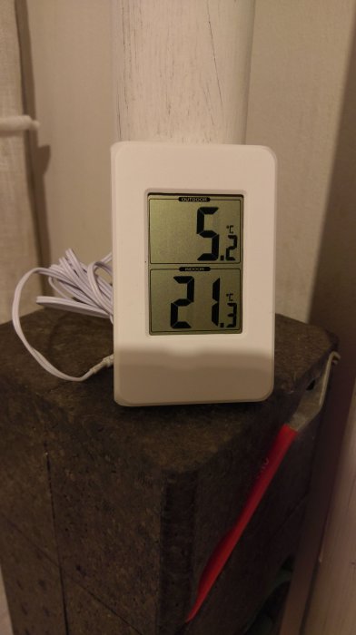 Digital termometer visar utomhus- och inomhustemperatur på en isoleringspanel.