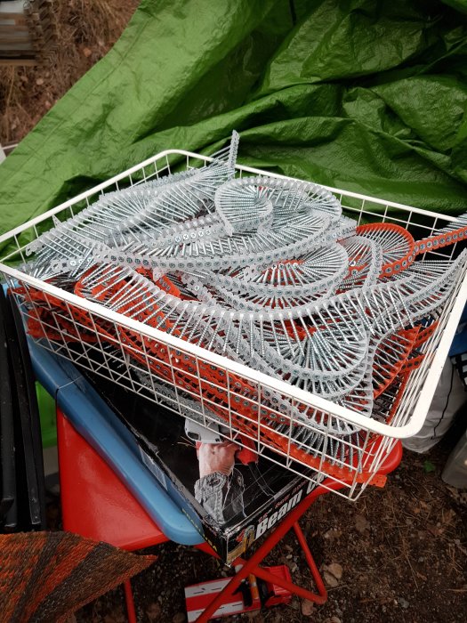 En trådback fylld med bandskruv för olika material och en del av ett kedjesvärd.