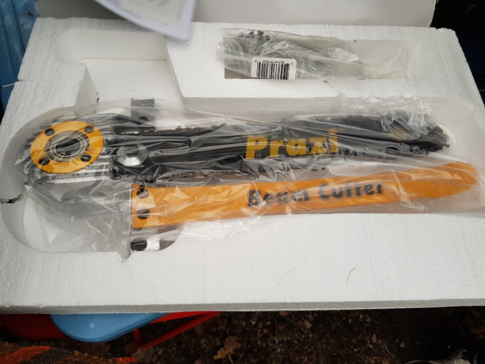 En kedjesvärdsanordning förmonterad på en klinga, förpackad i plast och vadderat skummaterial.