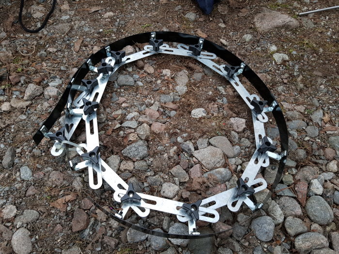 Trådback med olika storlekar av bandskruvar utlagda på grusunderlag, verktyg för bygg- och renoveringsprojekt.