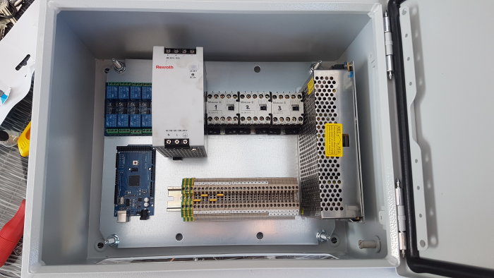 Elskåp med industrikomponenter innan montering, inklusive relämoduler och terminalplintar.