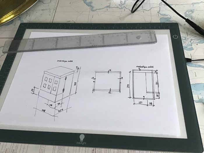 Ritningar av en byggnad med måttangivelser på ett ritbord med linjal.