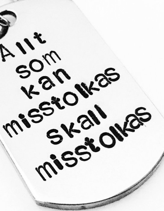 Nyckelbricka med texten "Allt som kan misstolkas ska misstolkas" i svart text mot vit bakgrund.