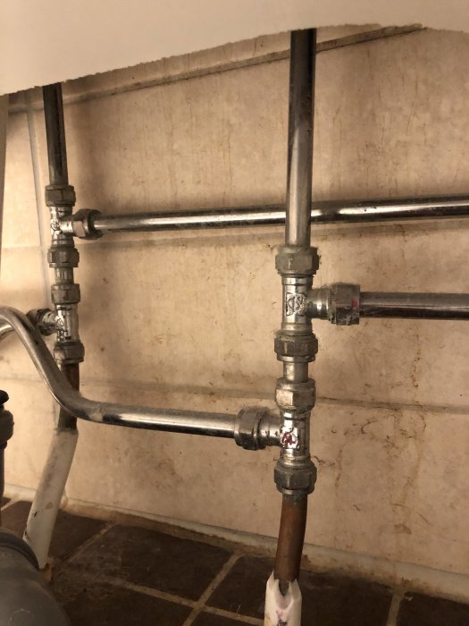 VVS-installation med koppar- och stålrör som fördelar vatten till badkar, dusch och handfat.