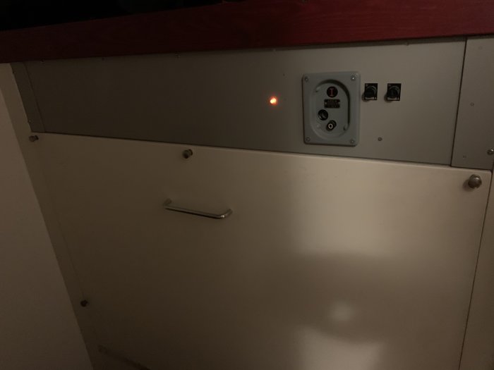 Panel av värmesystem med kontrollbrytare och en röd indikeringslampa.