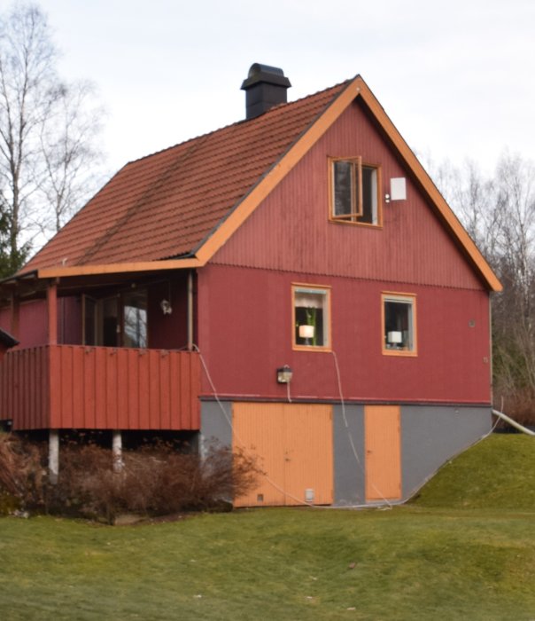 Tvåvånings hus med röd fasad och plåttak, till synes nytt, jämfört med ett äldre tillstånd.