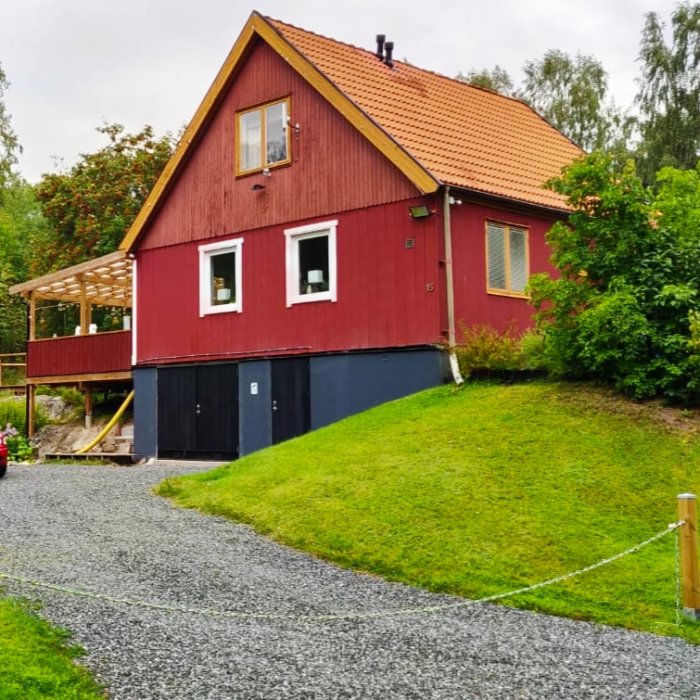 Rödmålat hus med tegeltak, vit snickarglädje och nyanlagd trädäck.