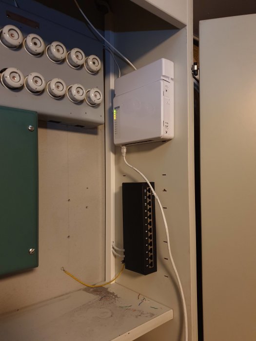 Ett nätverksskåp med switch och patchpanel installerat bredvid en elcentral.