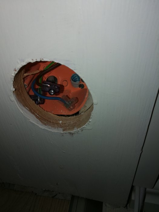 Apparatdosa i vägg med öppet hål och elektriska kablar synliga, redo för installation av väggkontakt.
