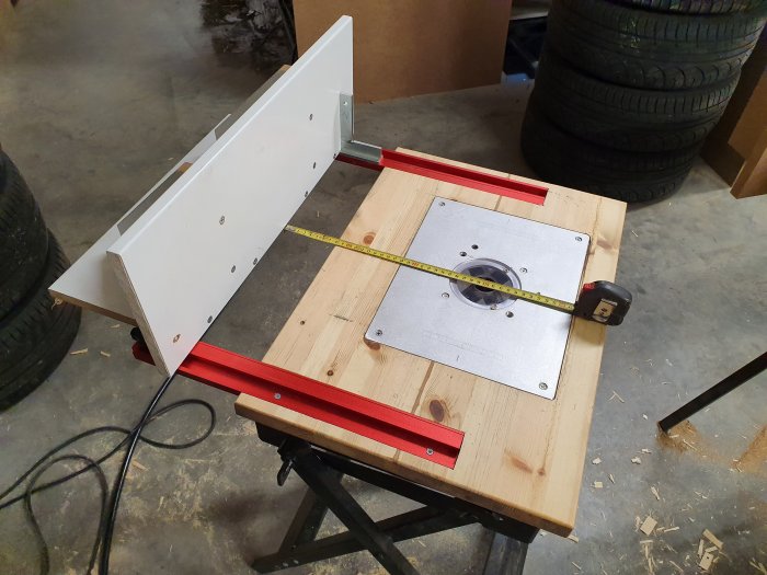 Ett nyligen byggt träfräsbord med metalliskt anhåll och inbyggd mätplatta, mätkabel dras över bordet.