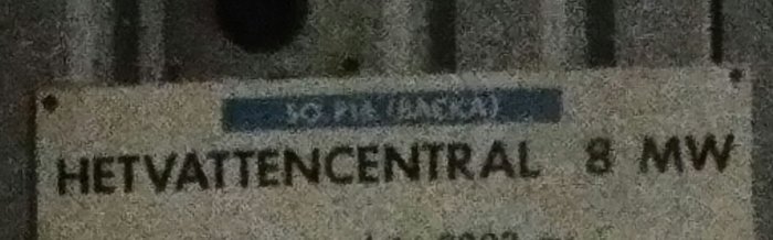 Skylt med texten "HETVATTENCENTRAL 8 MW" som indikerar en anläggning, tagen på natten.