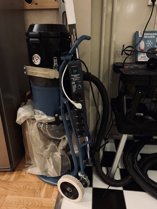 En ny dammsugare med autostart och diverse verktyg i ett rörigt utrymme.