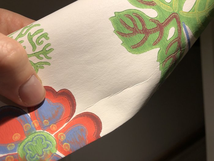 Hand som håller tapet med en stor spricka som går genom mönstret.