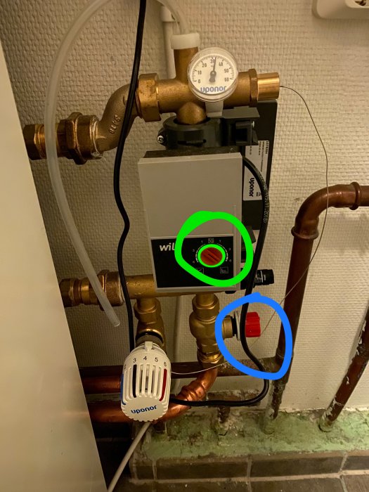 Uppvärmningssystem med termostat inställd mellan 2 och 5,5 och rör märkta med grönt och blått för olika temperaturer.