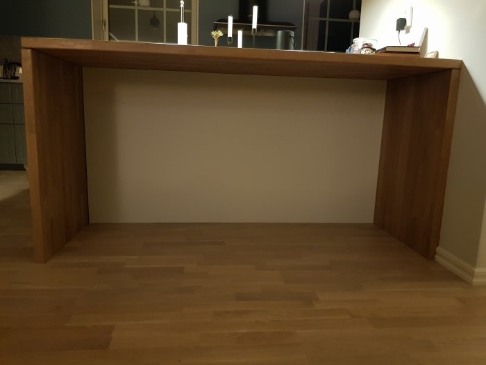 Träskiva målad i väggfärg installerad som fot på konstruerat träbord på ett parkettgolv.