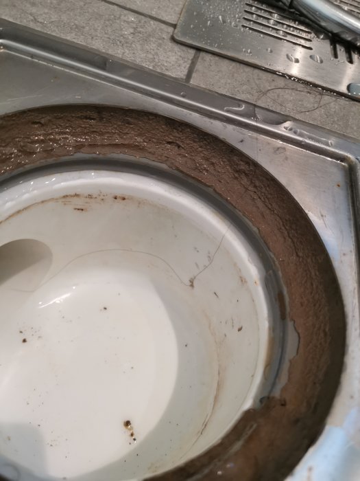 Närbild av golvbrunnen i ett renoverat badrum med synliga tätskikt och sil.